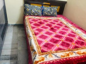 a bed in a room with a pink comforter and pillows at Lara Homestay 2bhk in Secunderabad