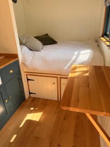 a small room with a bed and a wooden table at Shepherds Hut in St Austell