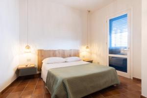a bedroom with a bed with two lamps and a window at Orsola Apartments in Favignana