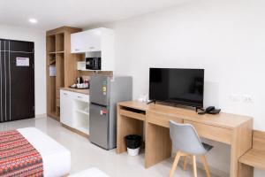 a room with a television and a desk with a chair at Christella Hotel Laemchabang in Si Racha