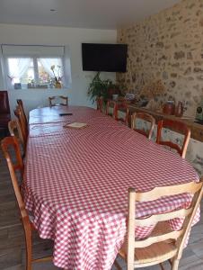 a dining room table with a red and white checkered table cloth at Chambre familiale in Voutré