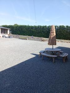 a picnic table with an umbrella and a bench at Chambre familiale in Voutré