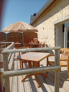 a wooden table and chairs and an umbrella on a deck at Chambre familiale in Voutré
