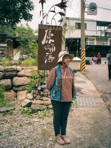 a woman wearing a hat standing in front of a sign at 蘭姐的民宿 in Taitung City