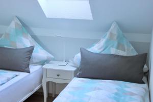 a bedroom with two beds with pillows and a table at Haus Witten Höhen Ferienwohnungen in Cuxhaven