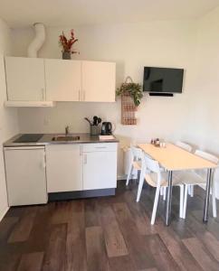 a kitchen with a table and white cabinets and a table and chairs at Vorbasse Holiday Apartments in Vorbasse