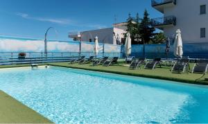 a large swimming pool with chairs and umbrellas at villa oltremare resort in Bagheria
