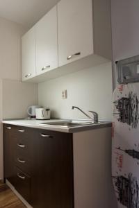 a kitchen with white cabinets and a sink and a refrigerator at The Old Captain Hostel in Burgas City