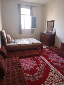 a bedroom with a bed and a window and a red rug at Home Room in Ghukra
