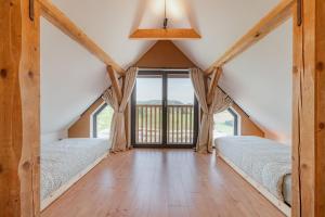 two beds in a attic bedroom with a window at Hiša pri Lipi in Pristava pri Mestinju