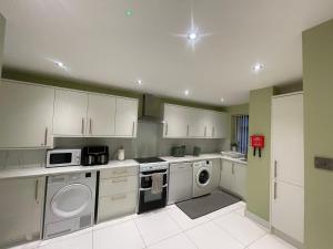 a kitchen with white cabinets and a washer and dryer at Silverhill in Bradford