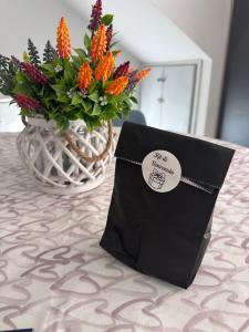 a black bag sitting on a table next to a vase of flowers at ARIEL'S house in San Benedetto del Tronto