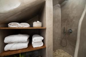 a bathroom with white towels on a wooden shelf at Petit Suite in Emporio +22 photos
