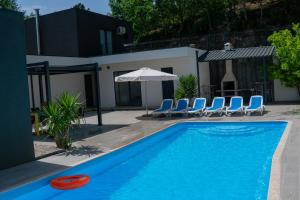 a blue swimming pool with a frisbee and chairs at Villa Travessa das Lages in Vieira do Minho