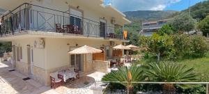a house with a balcony and tables and chairs at Lambrini Studios in Parga