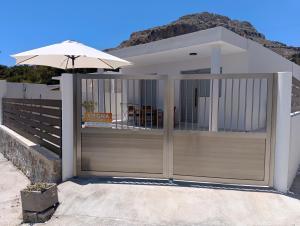 a house with an open gate with an umbrella at Stegna Holiday 2 in Archangelos
