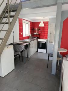 a kitchen with red walls and white cabinets and a table at Irida's House in Xylokastro +12 photos