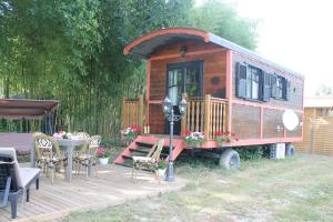 a tiny house sitting on a deck with a table at roulotte de charme avec jacuzzi privé in Beaupouyet