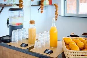 a counter with two bottles of orange juice and a basket of oranges at Quinta dos Vales Wine Estate in Lagoa