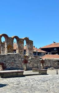 an old stone wall with arches in a courtyard at hostel FARA in Nesebar