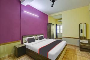 a bedroom with a large bed and a purple wall at Collection O EXPRESS SUITES in Calicut +19 photos
