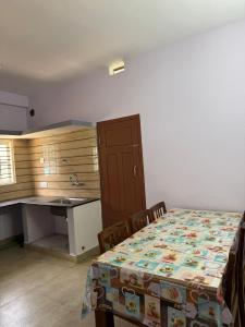 a kitchen with a table and a desk with a table and chairs at Janani service apartment in Kushālnagar
