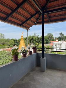 a patio with potted plants and a temple in the background at Janani service apartment in Kushālnagar
