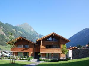 uma grande casa de madeira com montanhas ao fundo em EdelWeiss AlpinLodge em Matrei in Osttirol