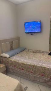 a bedroom with a bed with a tv on the wall at Rahej home in Bandar al Manşūrah