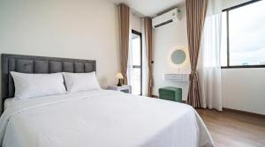 una camera da letto con un grande letto bianco e una finestra di Tittower a Bangkok