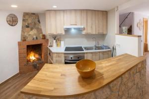 a kitchen with a wooden counter top with a fireplace at Cal Folquer in Alentorn