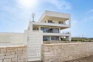 a white house with a stone wall and a fence at Wanderlust Experience Costa Sud in Bari