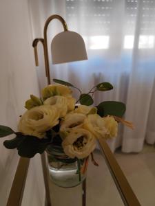 Eine Vase mit gelben Rosen stand auf einem Tisch. in der Unterkunft Li Brilli in Felline