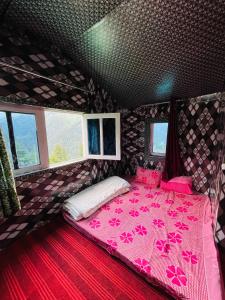 a bedroom with a pink bed in a room with windows at Skyblue cafe in Tosh