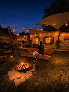 a man sitting on a bench next to a fire pit at Dimore Di Charme Lago Matese in San Gregorio