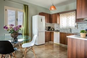 a kitchen with a glass table and a white refrigerator at Aphrodite Blue in Trapezaki