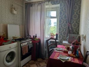 a kitchen with a table and a stove and a window at Квартира над Парусом in Zhmerynka