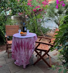 a table with a purple table cloth and a bottle of wine at Aphrodite Villas Halki - Studio Rosa in Halki +1 photo