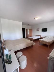 a room with two beds and a table and a tv at Nedzarici sobe in Sarajevo