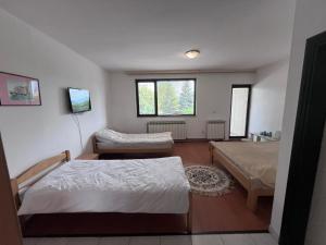 a bedroom with two beds and a couch and a tv at Nedzarici sobe in Sarajevo