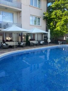 a swimming pool with umbrellas and chairs and a building at Peshev Family Hotel Nesebar in Nesebar