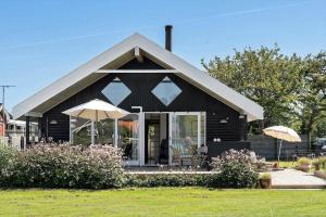 a black house with two umbrellas in a yard at FY222-Otterup-Klovervaenget-13 in Otterup
