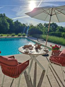 a table with an umbrella next to a pool at Casa Oksana in Castelnau-de-Montratier