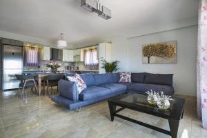 a living room with a blue couch and a table at Villa Karavias by Villa Select in Trapezaki
