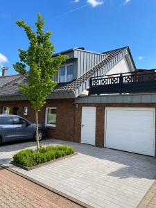 a house with two garage doors and a tree at FeWo Auszeit eigene große Terrasse mit Strandkorb und Grill in Wesel +3 photos