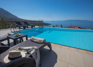 a pool with chairs and a table with a view at Lourdas Beach View by Villa Select in Lourdata