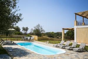 a swimming pool with chairs and a table and a table at Villa Karavias by Villa Select in Trapezaki