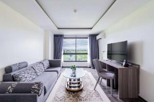 a living room with a couch and a tv at The Grand Palm Villa in Ban Bang Phrao