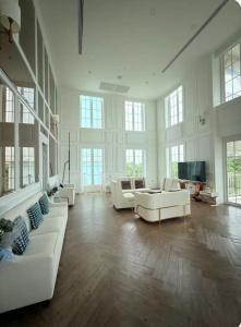 a large living room with white furniture and windows at Pattaya Private Beach - Grand Florida Beachfront Condo Resort in Na Jomtien