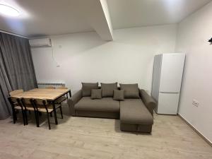 a living room with a couch and a table and a refrigerator at Apartament Meraki Resort&Spa in Năvodari